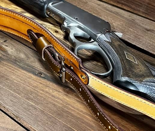 Classic Distressed Leather Rifle Sling laying next to a rifle gun
